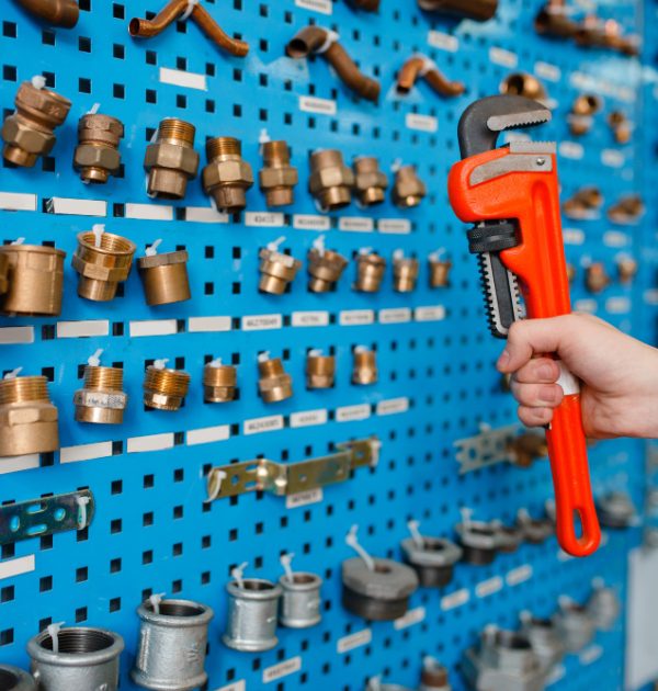 plumber-hand-holds-pipe-wrench-showcase-plumbering-store-man-buying-sanitary-engineering-shop